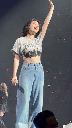 a woman standing on top of a stage with her arms in the air and holding a microphone