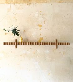 two vases with flowers are sitting on a wooden shelf in front of a wall