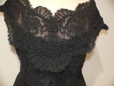 Gorgeous vintage black alencon lace blouse for evening wear. It is labeled Watters and Watters with the fabric contents and care pictured. My guess is 60's - 80's . This lace is fabulous with heavy cording around the flowers in an all over floral pattern. The top has slight off the shoulder wide straps or sleeves which fall to a v shape on both front and back. It is fitted along the waist. All edges have the eyelash of the lace showing on the scalloped edging. Inside is lined in both a netting a Fitted Lace Bodice For Evening, Fitted Black Sheer Lace, Sheer Sleeveless Lace Top For Evening, Sheer Black Lace Top For Party, Elegant Sheer Lace For Evening, Fitted Scalloped Lace For Evening, Black Scalloped Lace Top For Night Out, Fitted Sheer Lace For Evening, Formal Sheer Lace Top