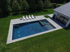 an aerial view of a swimming pool with lounge chairs on the lawn next to it