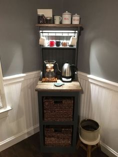 a coffee pot and kettle on top of a small table in a room with gray walls