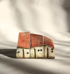 two small houses made out of bricks sitting on top of a white sheet