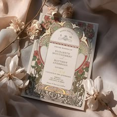 an ornate wedding card with flowers on the bottom and in the middle, surrounded by silk