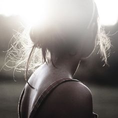 a woman with her hair blowing in the wind, looking off into the distance and to the side