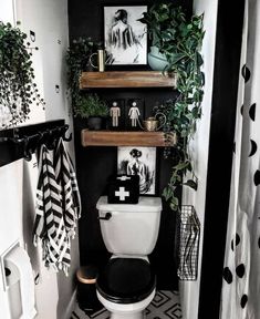 a black and white bathroom with shelves above the toilet, plants on the ledges