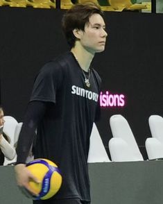 a young man holding a yellow and blue ball