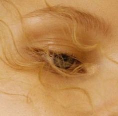 a close up view of a woman's hair and eye looking down at the camera