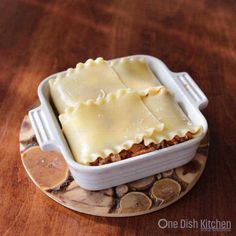 a casserole dish filled with lasagna sitting on top of a wooden table