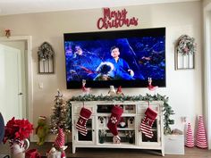 a flat screen tv mounted to the side of a wall in a living room with christmas decorations