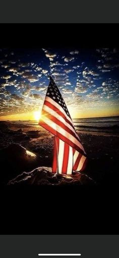 an american flag on the beach at sunset