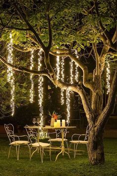 an outdoor table and chairs under a tree with lights