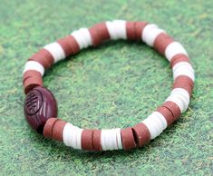 Youth Boy's American Football Themed Polymer Clay Trending Sports Themed Stretch Bracelet - Brown and White(Boring title. We know. We are trying to appease the algorithm deity). Football! Football! Football! This brown and white bracelets is inspired by the old pig skin (not literally, we are using a slang for the word football) hitting the field. Hut Hut Hike! Material Used:Green and Brown Polymer Clay Beads(1) Plastic Brown Football BeadNylon Stretch String Bracelets come in sizes: 5 inches an Cheap Casual Sports Beaded Bracelets, White Sporty Stretch Bracelet For Sports, Sporty White Stretch Bracelet For Sports, Football Hits, Browns Football, Jackson Mississippi, String Bracelets, Football Football, White Bracelets