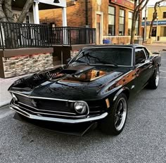 an old muscle car parked on the side of the road in front of a building