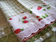 two pieces of cloth with strawberrys on them sitting on top of a tablecloth