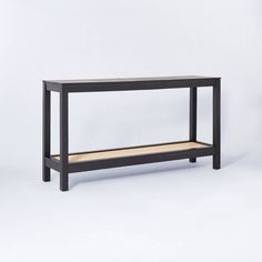 a black console table with two shelves on the bottom and one shelf below it, against a white background