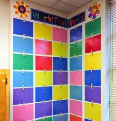 a colorful bulletin board with clothes pins attached to it and flowers on the back wall