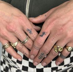 two people with tattoos on their hands holding each other's fingers and wearing matching rings