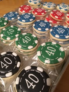 cupcakes decorated with casino chips and numbers are displayed in plastic wrappers on a table