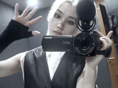 a woman is holding up a camera in front of her face and wearing black gloves