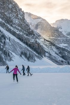 several people are skiing in the snow near mountains