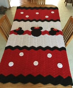 a crocheted mickey mouse blanket on top of a wooden table with two chairs