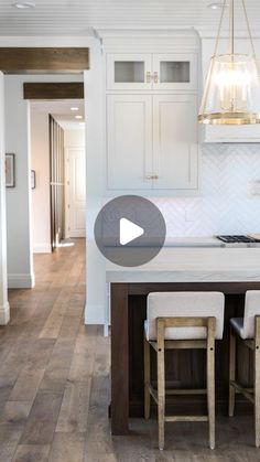 a kitchen with white cabinets and counter tops, an island in the middle is surrounded by bar stools