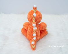 an orange crocheted stuffed animal with pearls