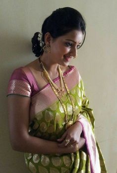 a woman in a green and pink sari with gold necklaces on her neck