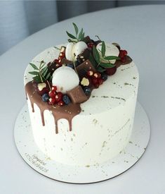 a white cake topped with berries and chocolate