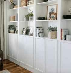 a living room filled with lots of white bookshelves covered in pictures and plants