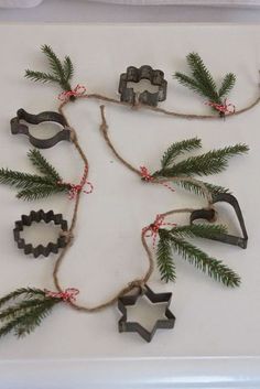 an ornament made out of cookie cutters and pine branches on a white surface