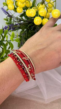 a woman's hand with yellow flowers and red bracelets on her left wrist