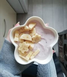 a person holding a bowl with bananas and yogurt on it in their hand