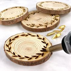 three wooden coasters with black and gold designs are being used to make coasters