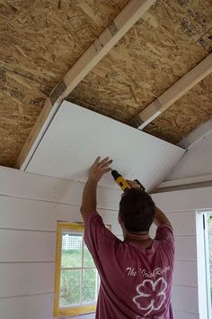 a man holding a beer bottle up to the ceiling in a room with unfinished walls