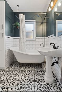 a white bathtub sitting next to a sink in a bathroom with black and white tile