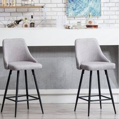 two gray bar stools sitting in front of a white brick wall and counter top