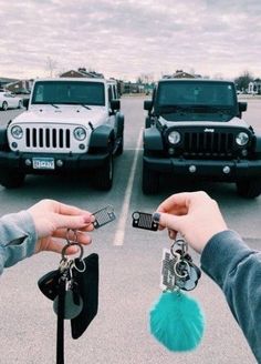 two people holding keys in front of jeeps