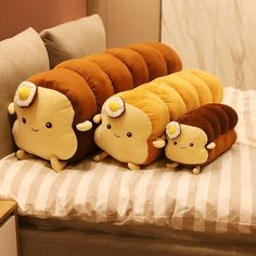 three stuffed animals sitting on top of a bed next to each other in the shape of caterpillars