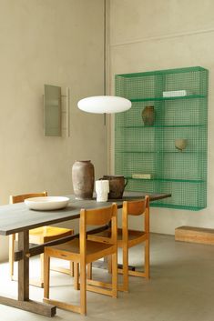 a dining room table and chairs in front of a wall with shelves on the side