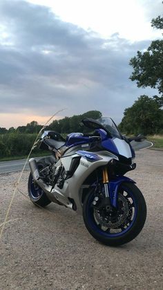 a blue and silver motorcycle parked on the side of the road