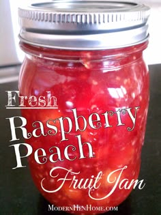 a jar filled with fresh raspberry peach fruit jam on top of a table