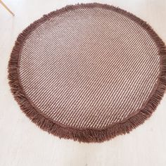 a brown round rug with fringe on the floor