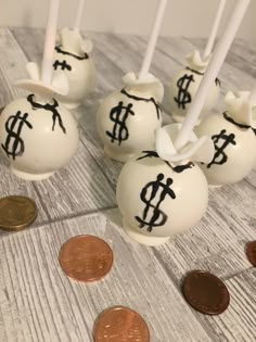 some white candy balls with black symbols on them and one penny sitting next to them