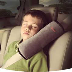 a young boy sleeping in the back seat of a car with a pillow on it