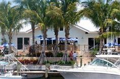 a boat is docked in the water next to some palm trees and houses with umbrellas on them