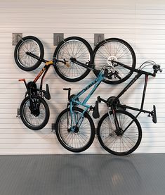 three bikes mounted to the side of a white wall with hooks on it's sides