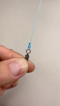 a hand holding a tiny necklace with a blue string