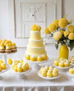 a table topped with yellow cakes and cupcakes