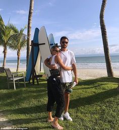 a man and woman standing next to each other in front of surfboards on the beach